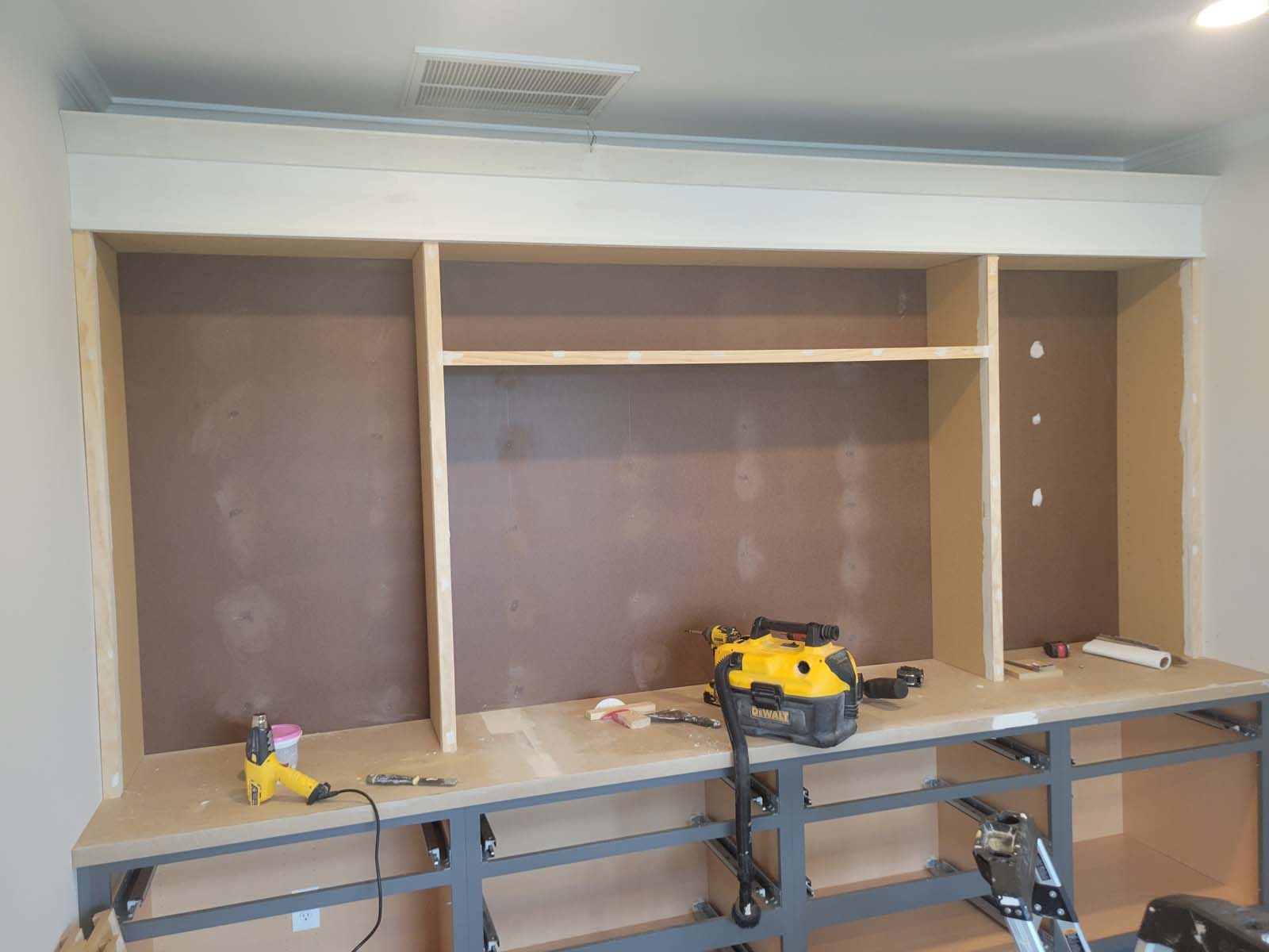 A large wooden cabinet is being built in a room.