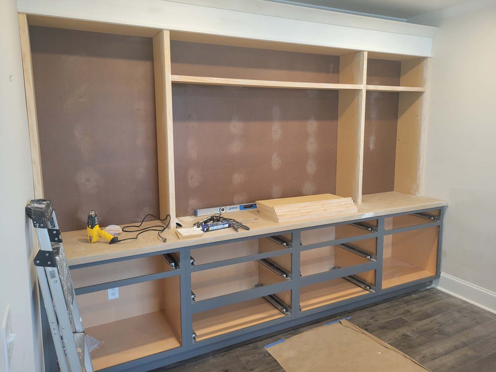 A room with a lot of shelves and drawers being built.