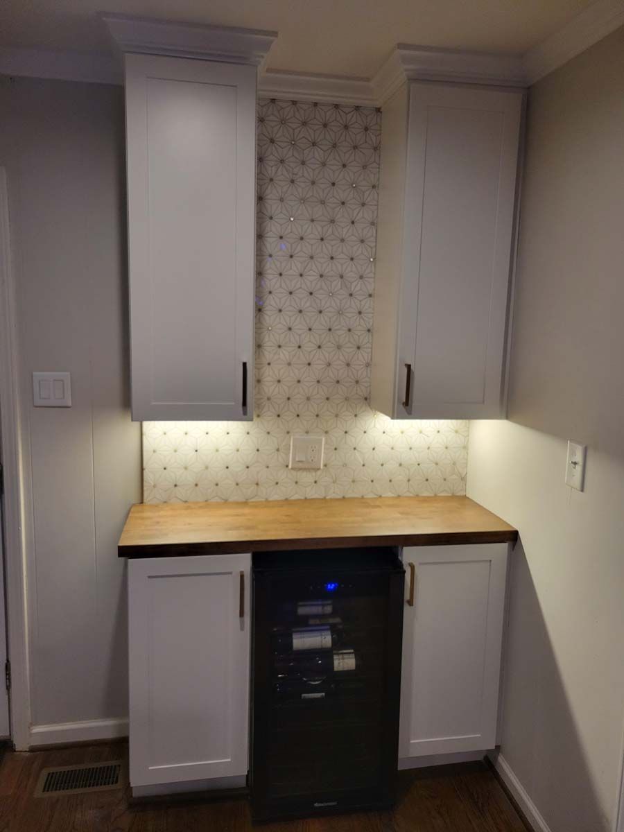 A kitchen with white cabinets and a black dishwasher
