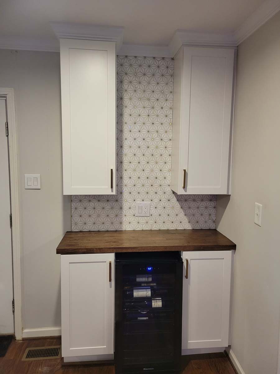 A kitchen with white cabinets and a wine cooler.