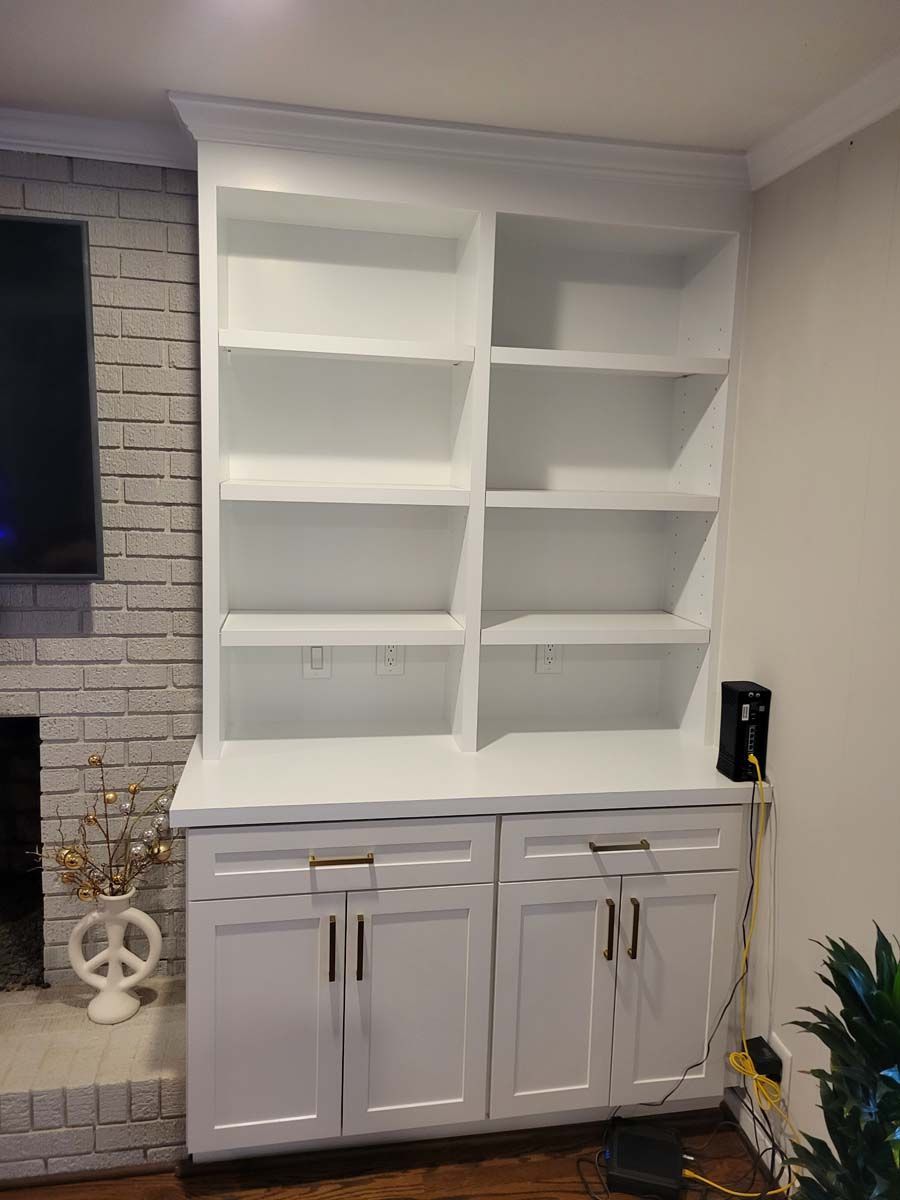 A living room with white cabinets and shelves and a fireplace.
