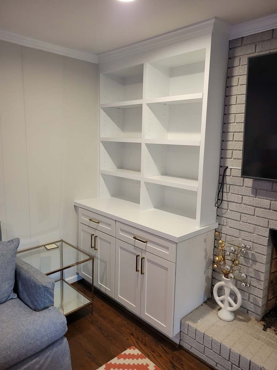 A living room with a fireplace , couch , shelves and a television.