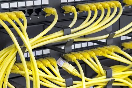 Yellow network cables plugged into a server rack in a data center.