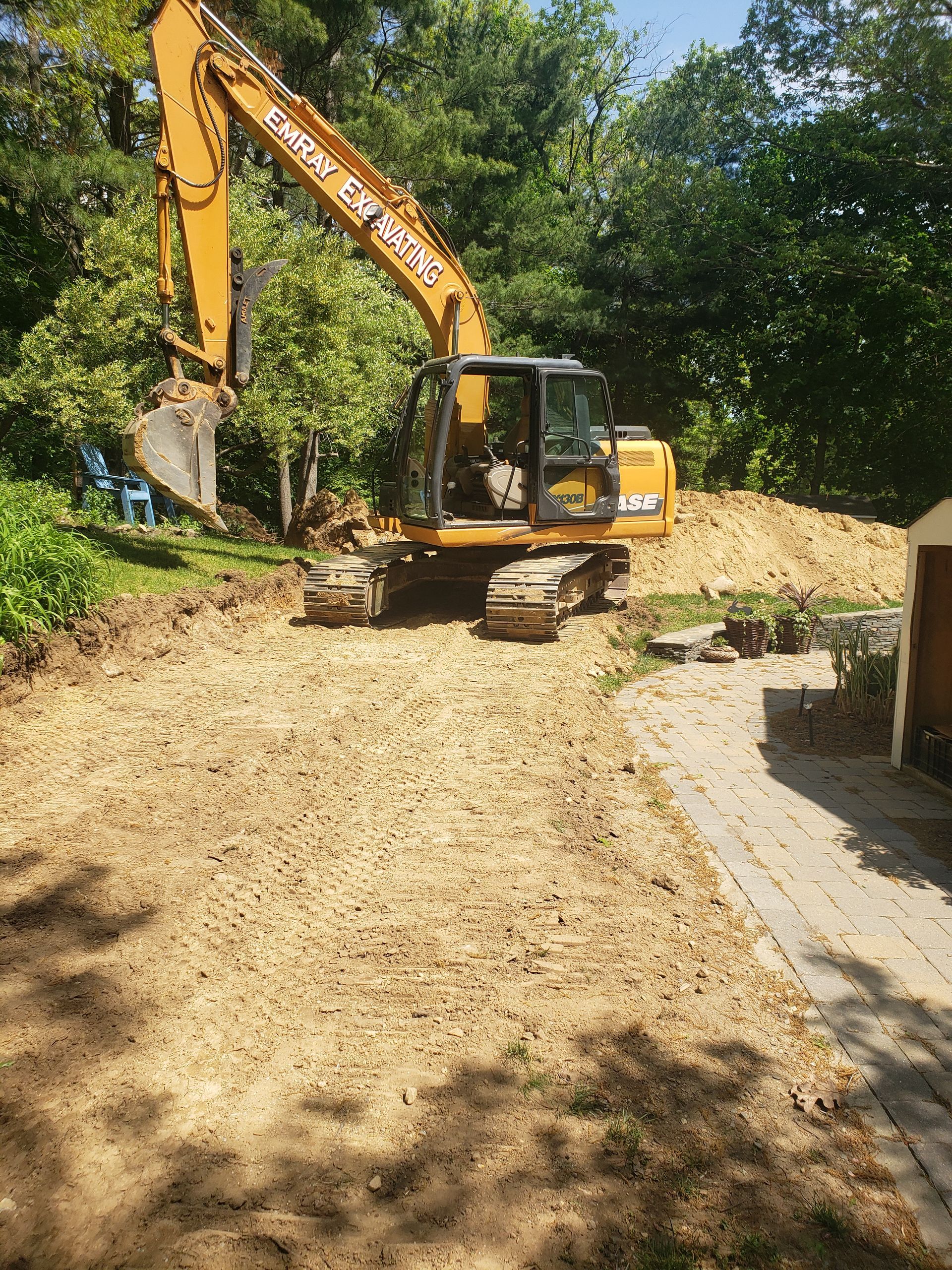 a large yellow excavator is digging a hole in a yard
