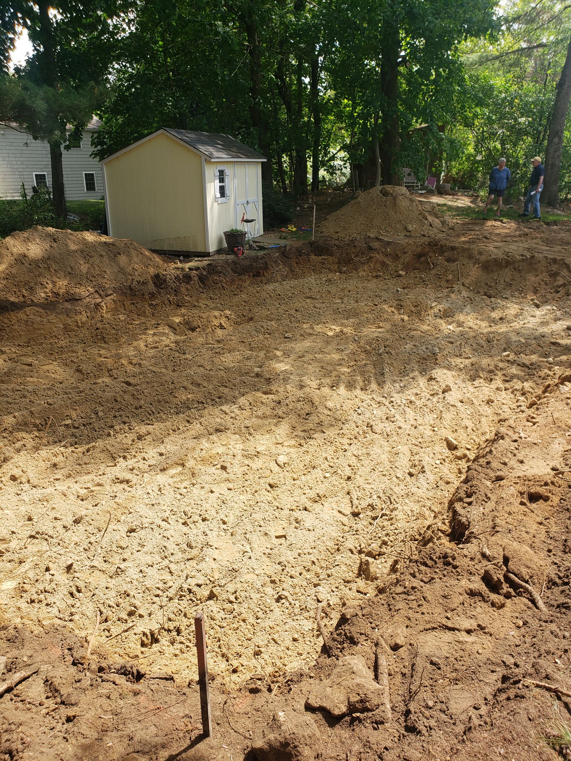 a shed is sitting in the middle of a dirt field next to a house