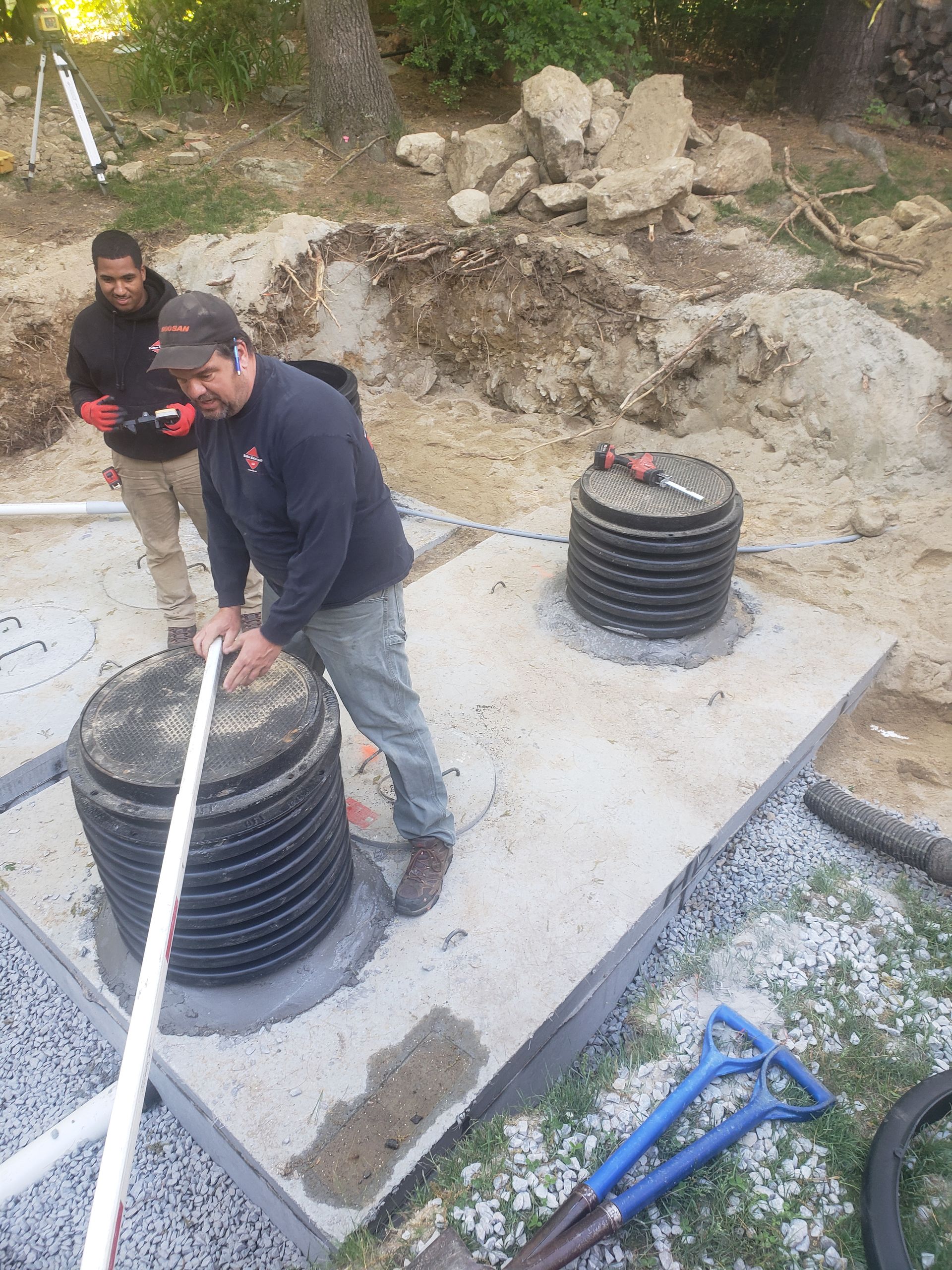 two men are working on a septic system in the dirt