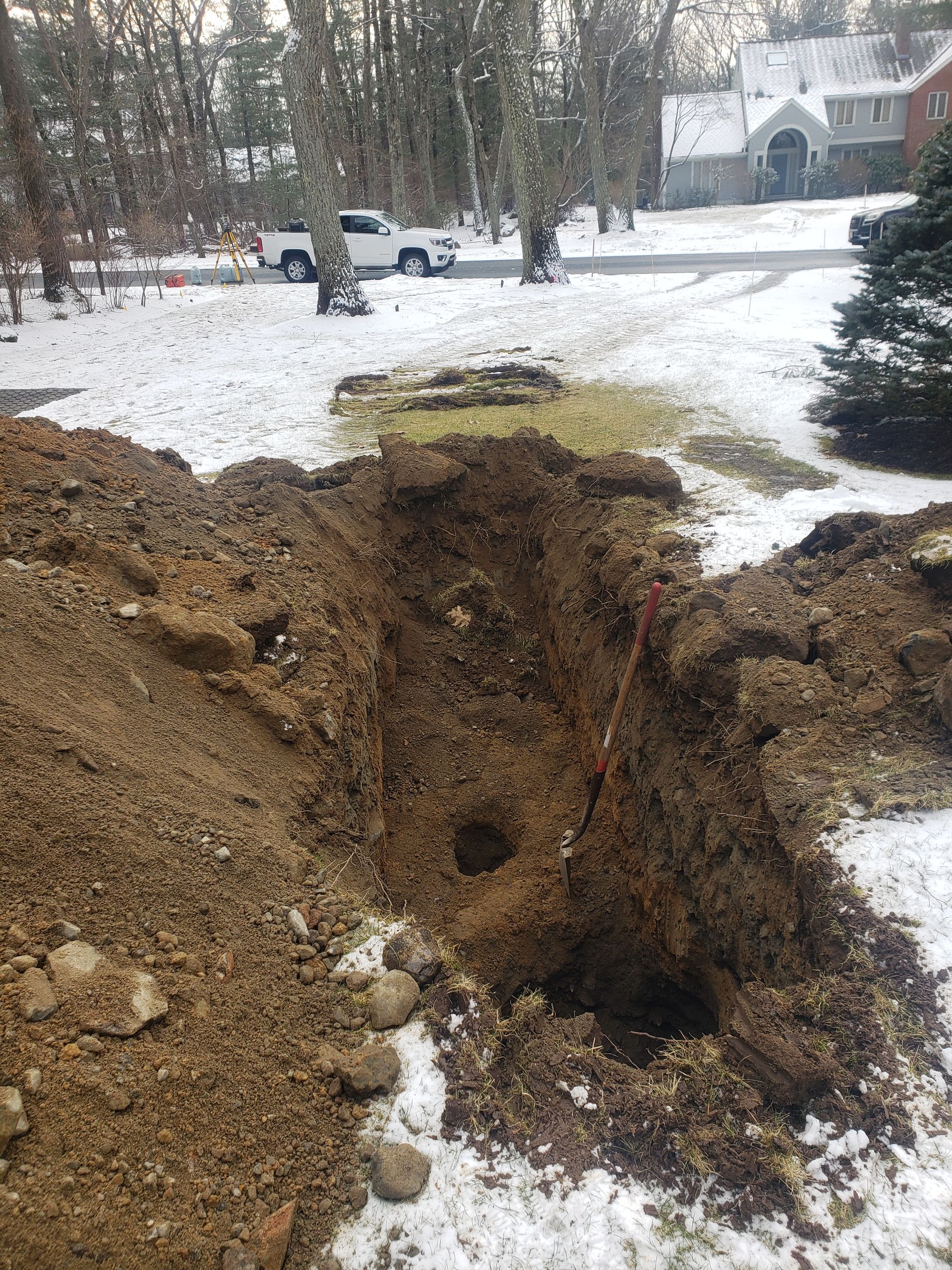 a large hole in the ground in the middle of a snowy yard