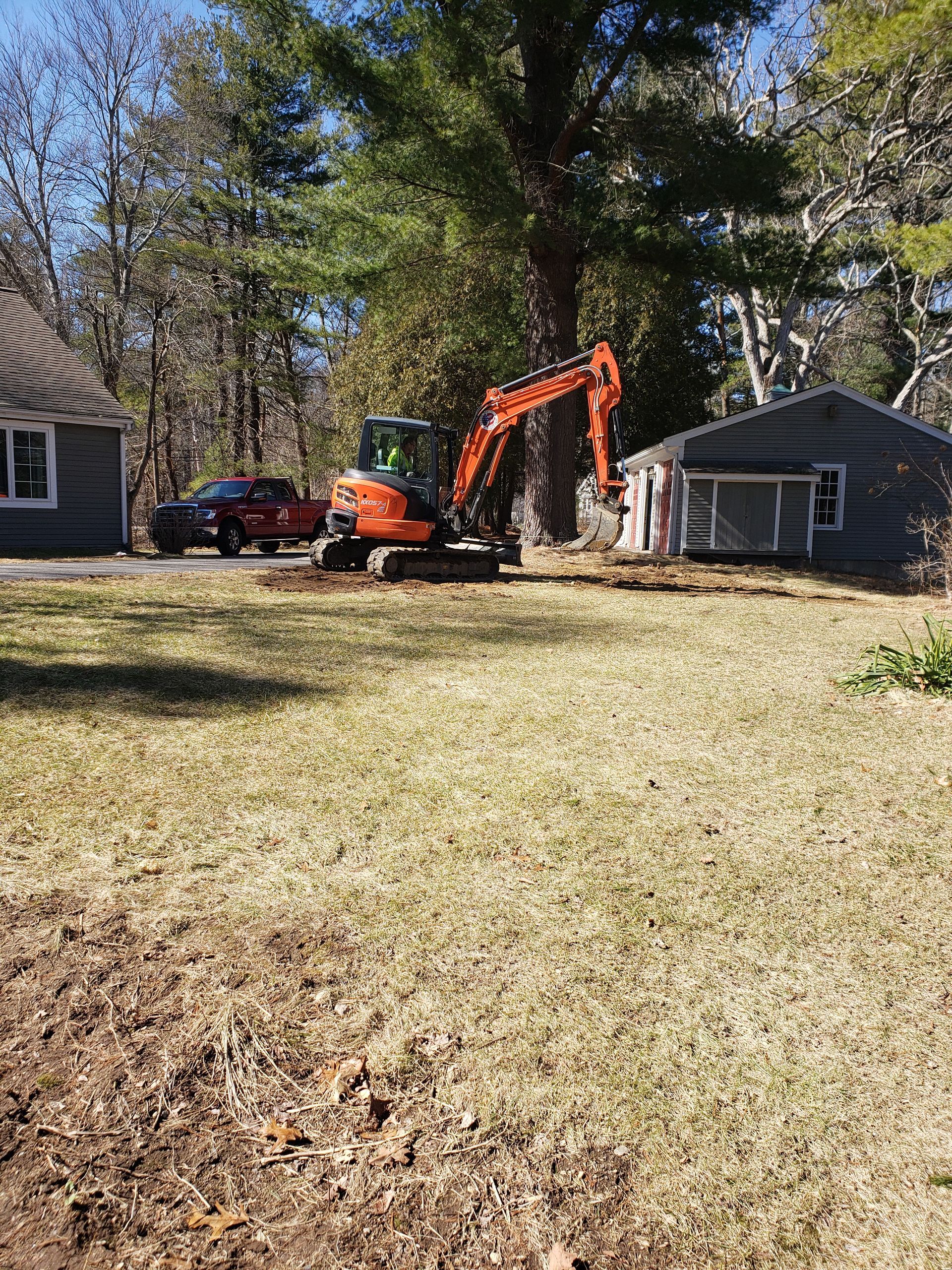 an excavator is moving dirt in a yard in front of a house
