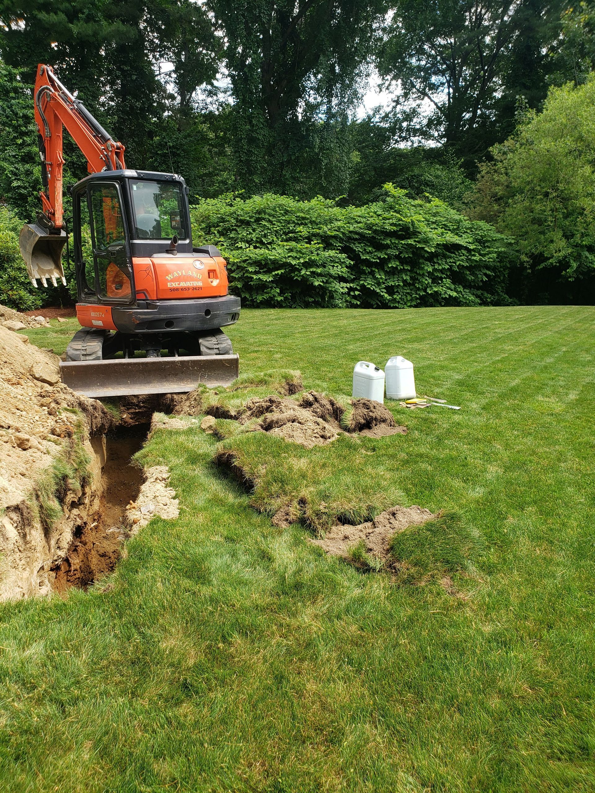 an orange excavator is digging a hole in the grass