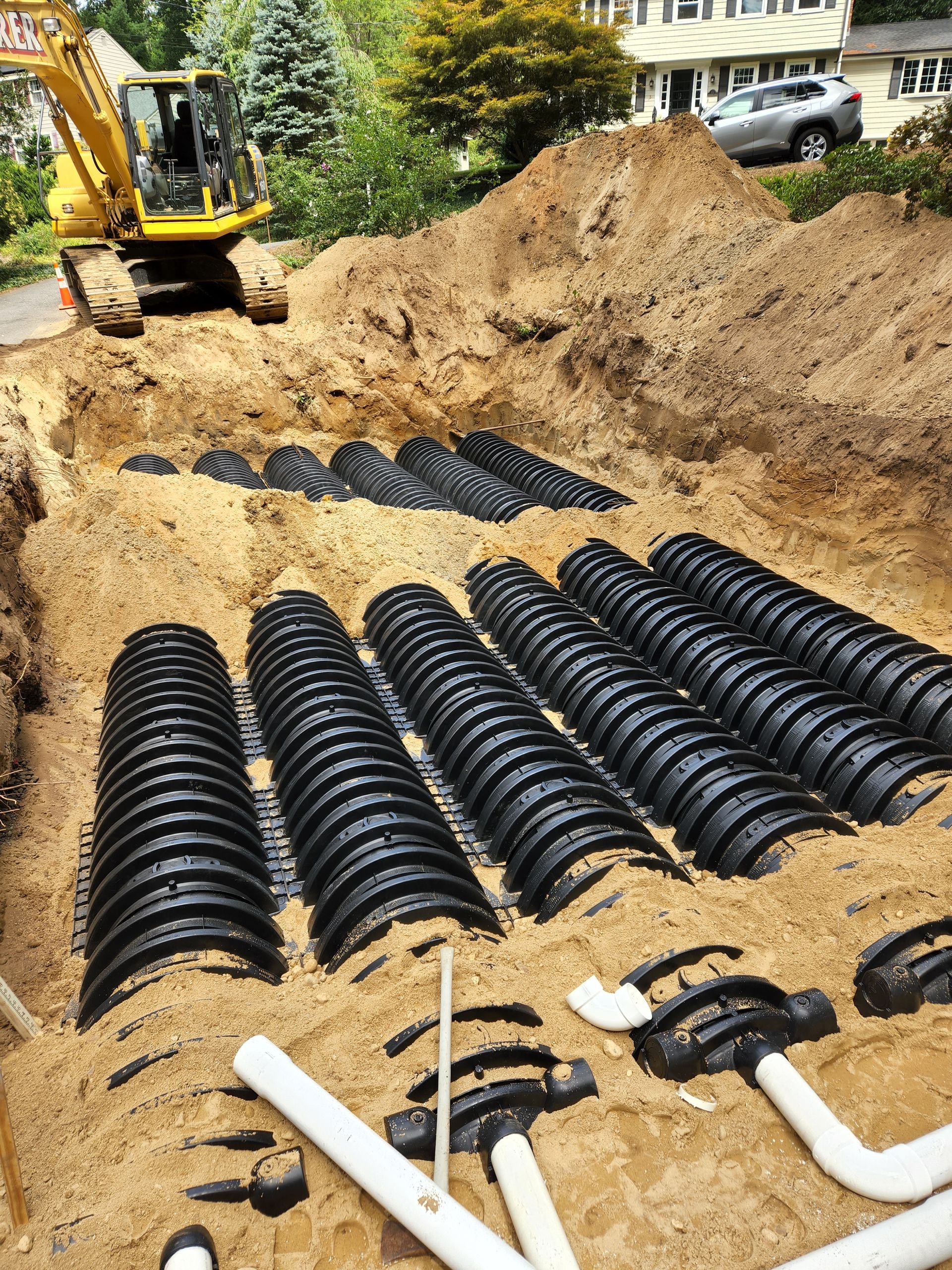 a yellow excavator is digging a septic system in the dirt