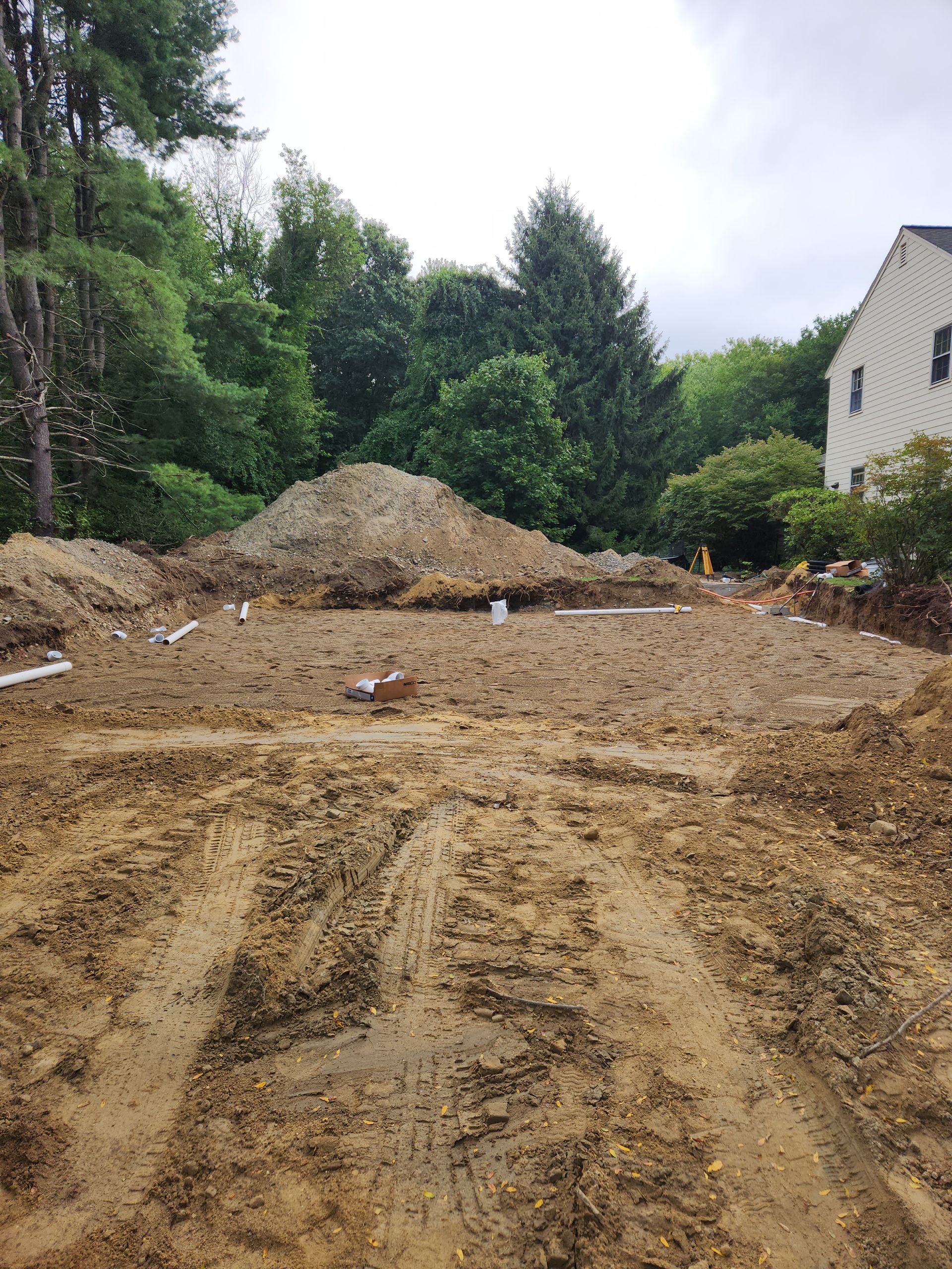 a large pile of dirt is sitting in the middle of a dirt field in front of a house