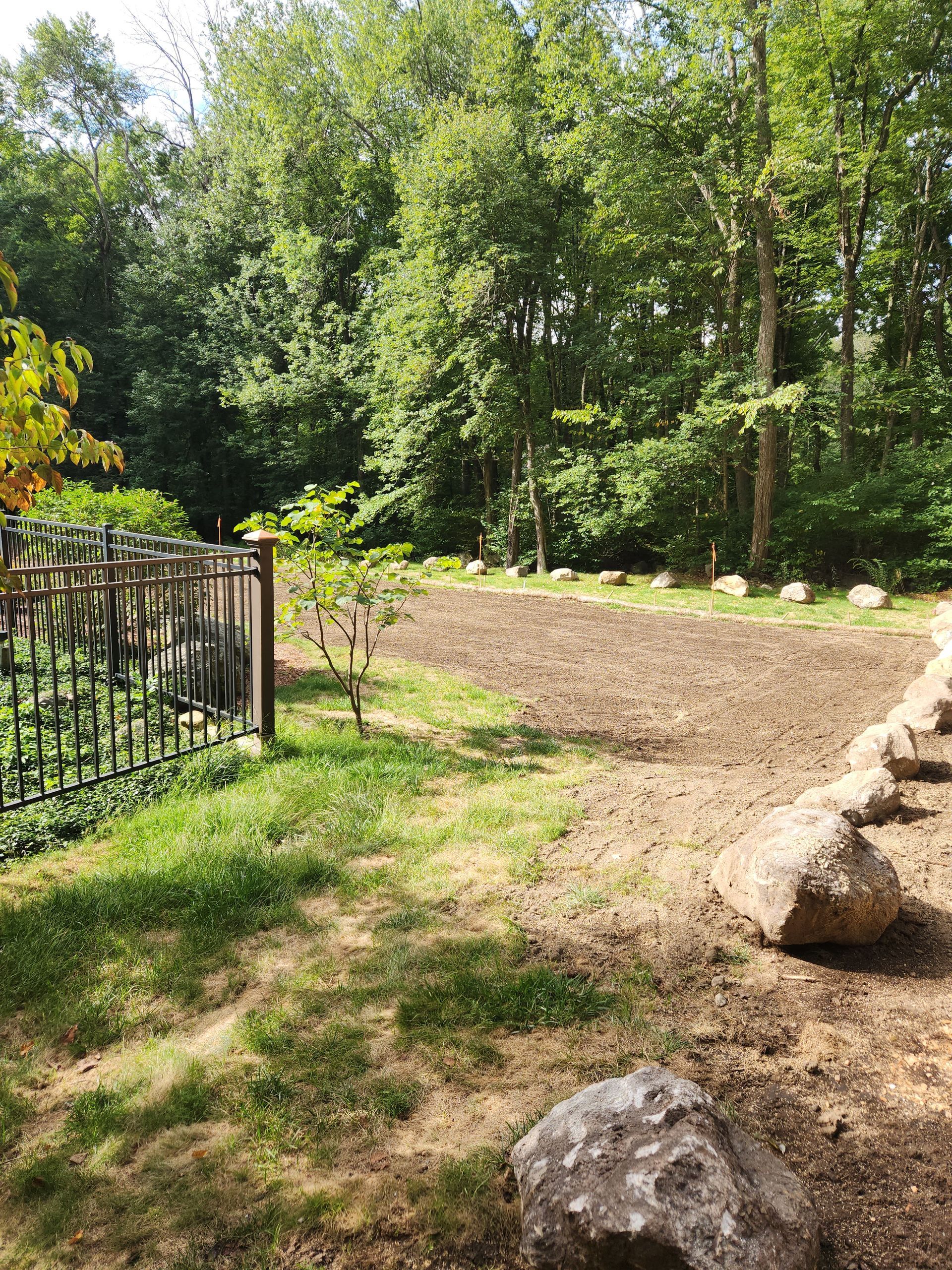 a fenced-in yard with rocks and trees in the background