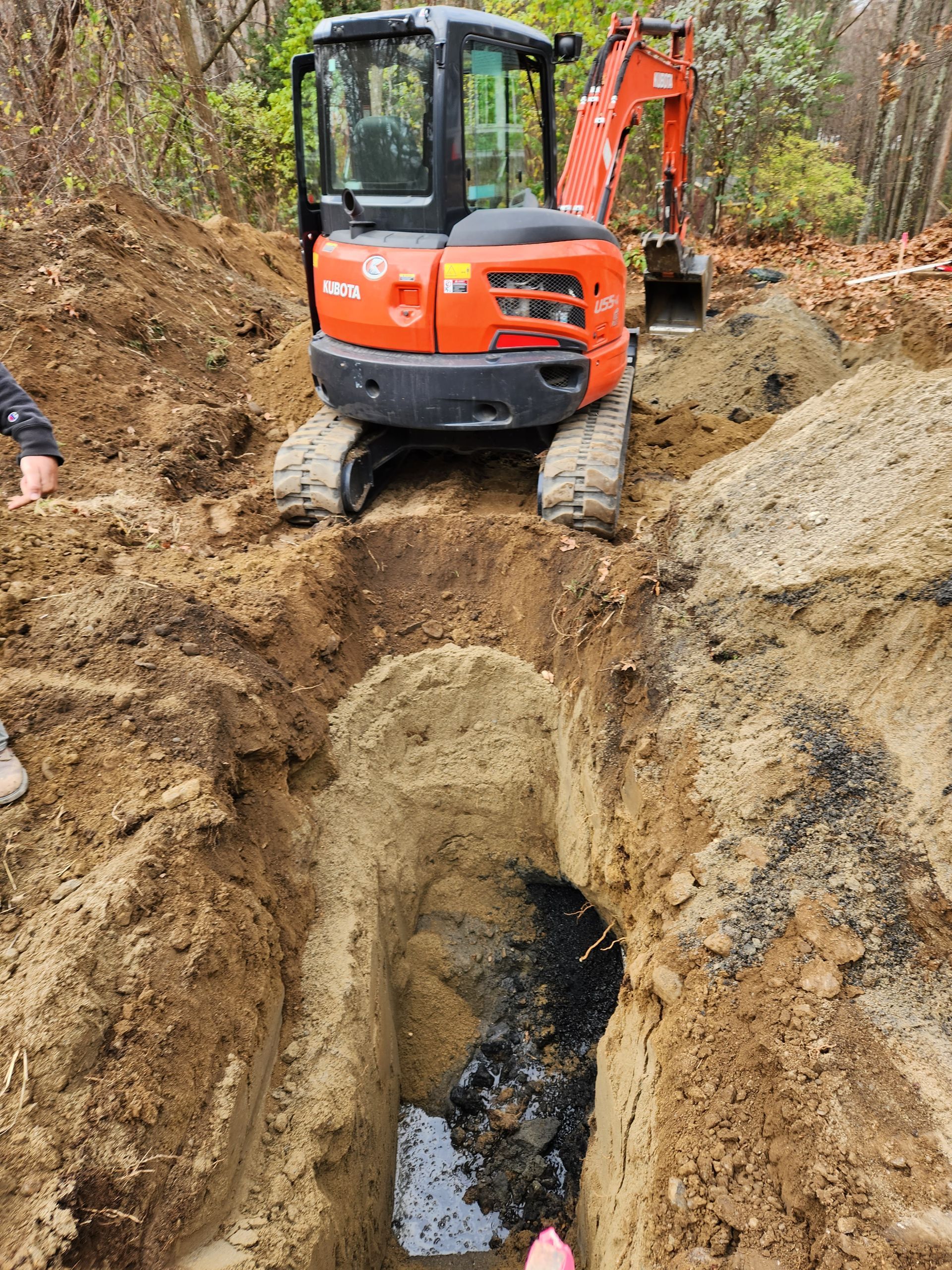 a small orange excavator is digging a hole in the dirt
