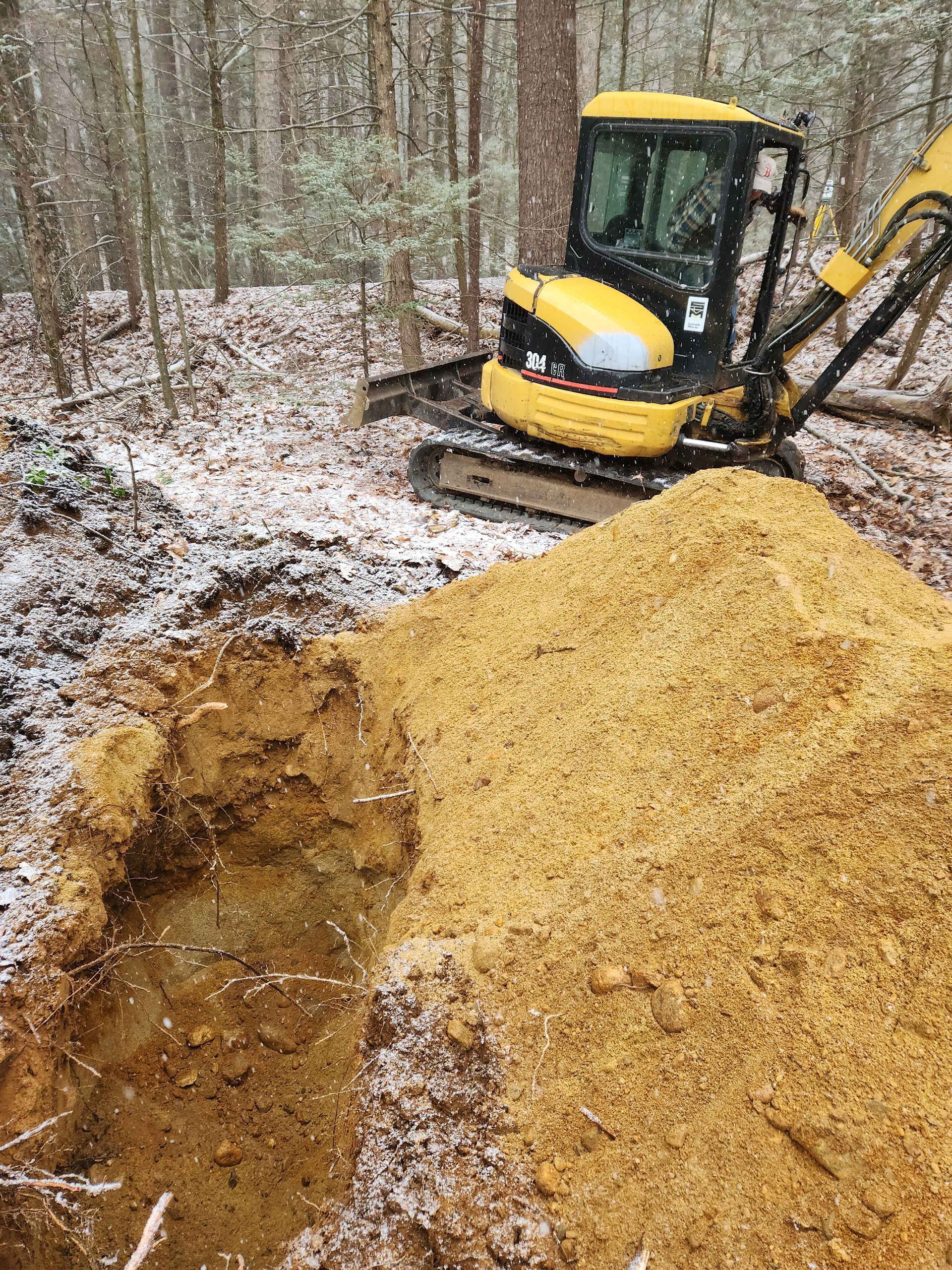 a yellow excavator is digging a hole in the woods