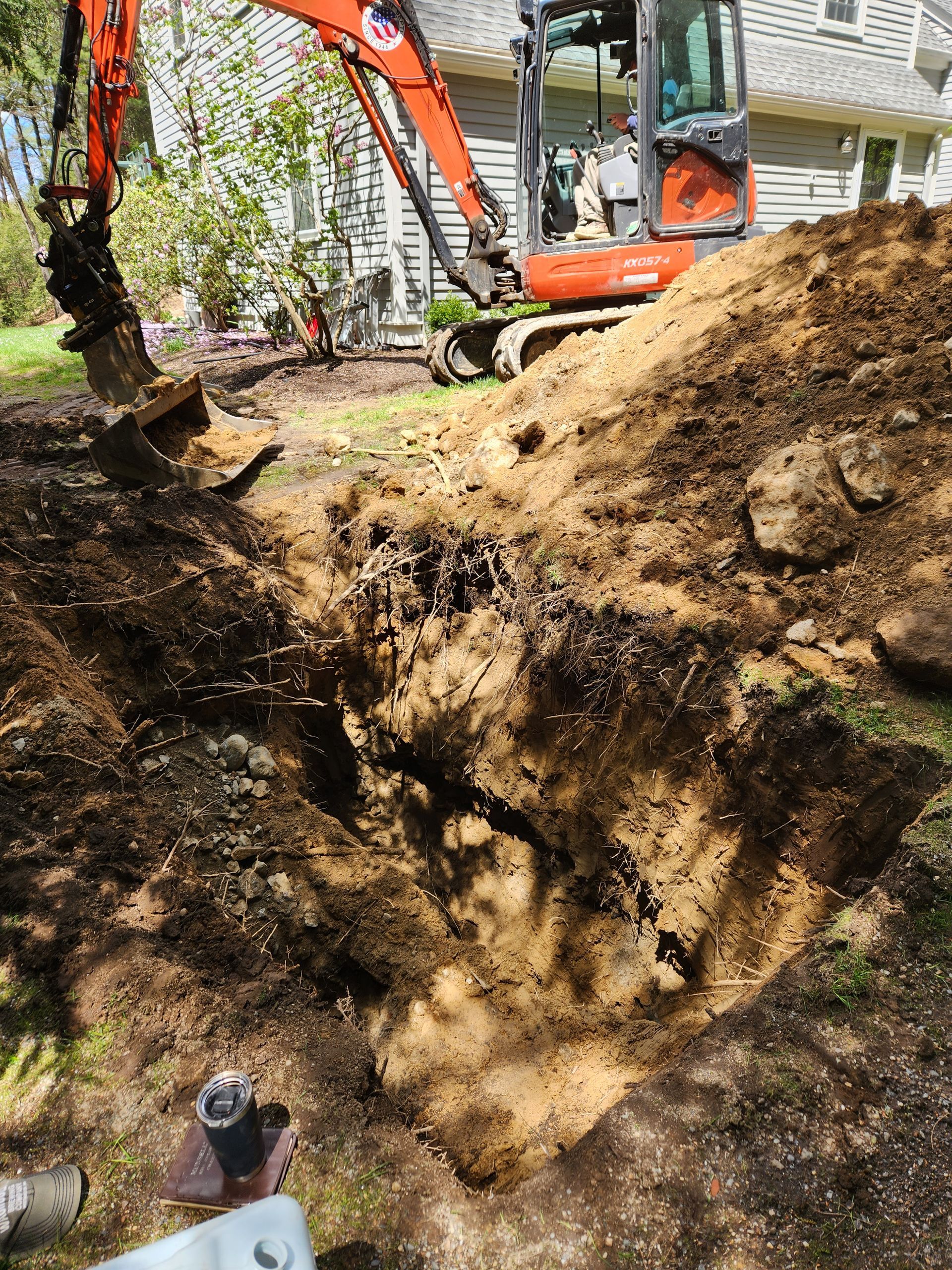 an excavator is digging a hole in the ground in front of a house