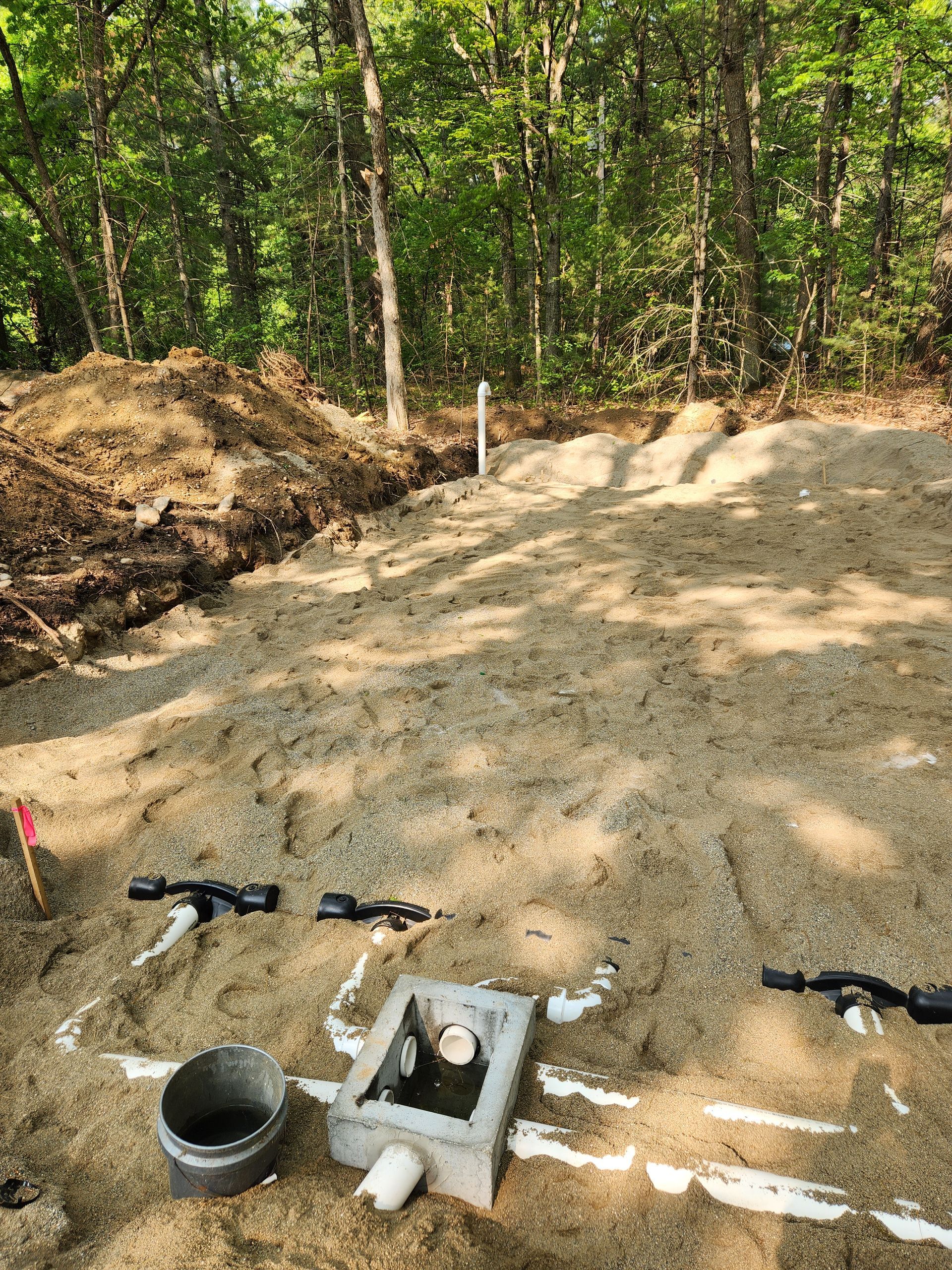 a concrete box is sitting on top of a pile of dirt in the middle of a forest