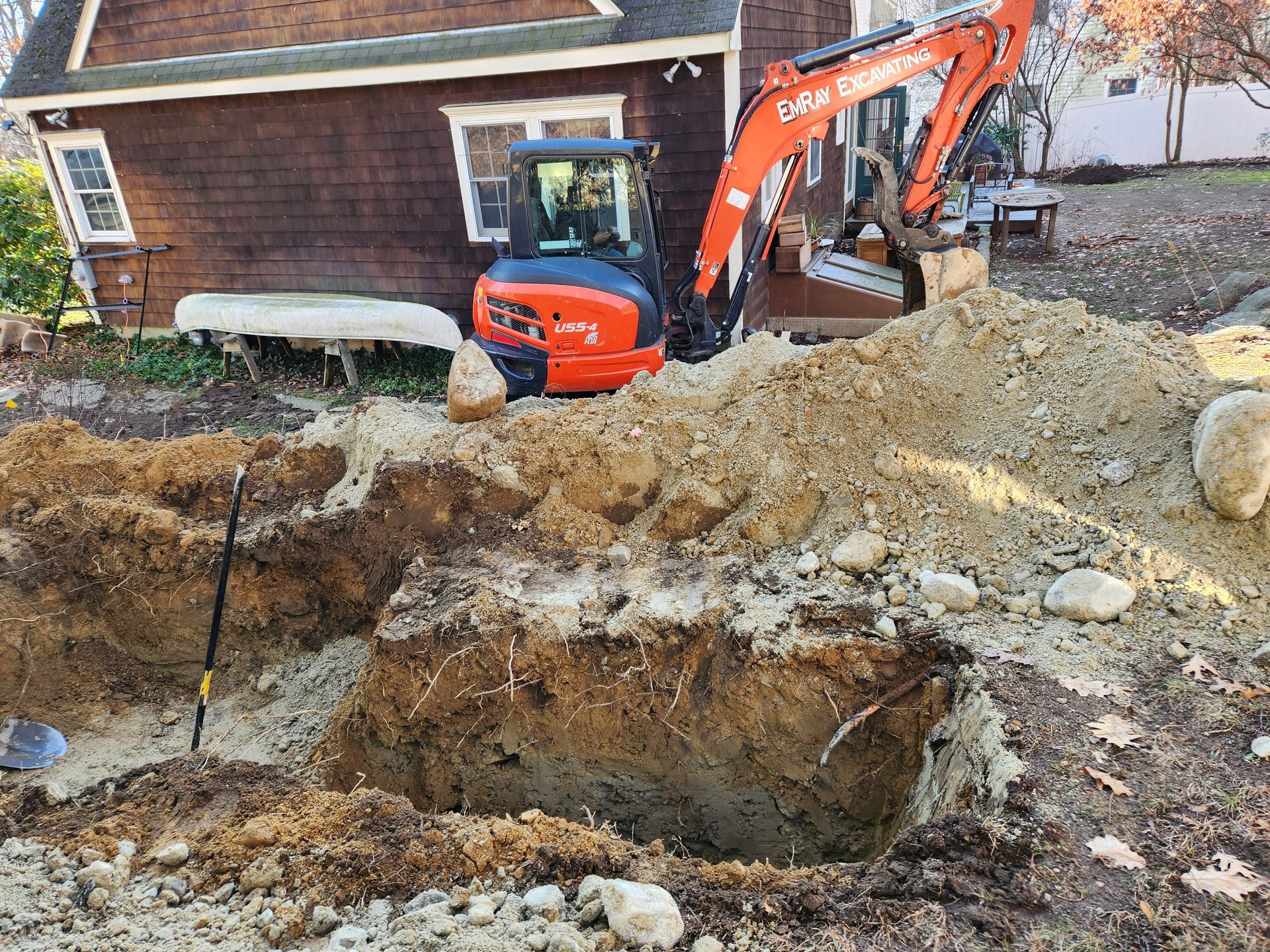 an excavator is digging a hole in the dirt in front of a house