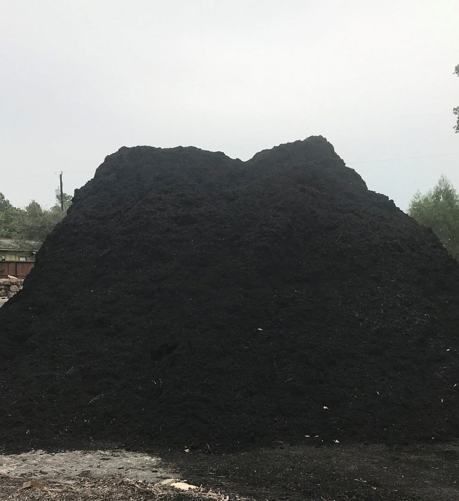 Large black coal pile outdoors against a pale sky