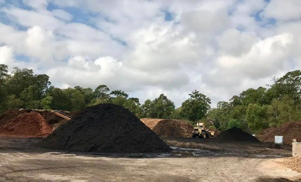 Large piles of gravel and dirt at a roadside construction site under a cloudy sky