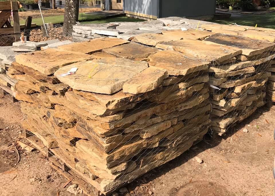 Stacked flat stone slabs outdoors on a dirt lot