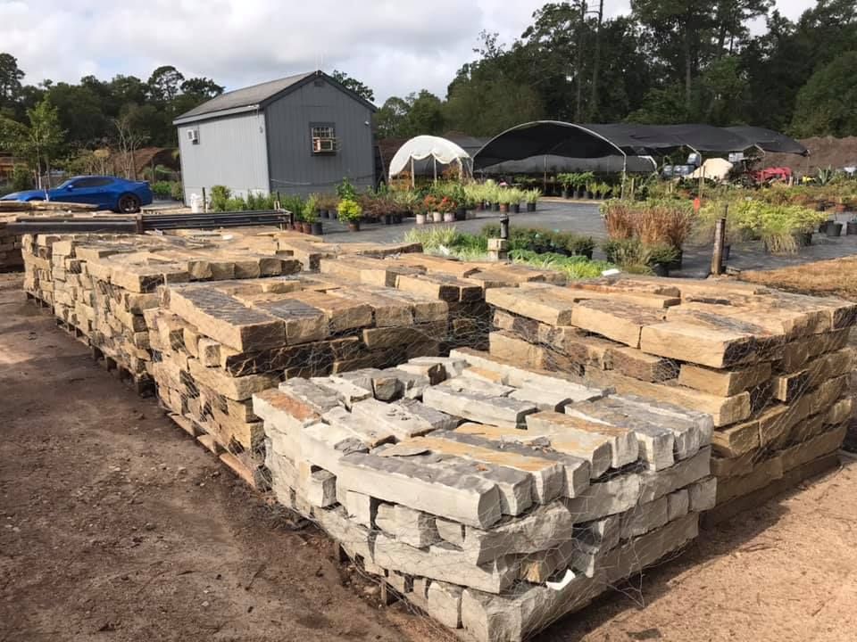 Stacked stone blocks in a garden yard with a shed and hoop greenhouse in the background.