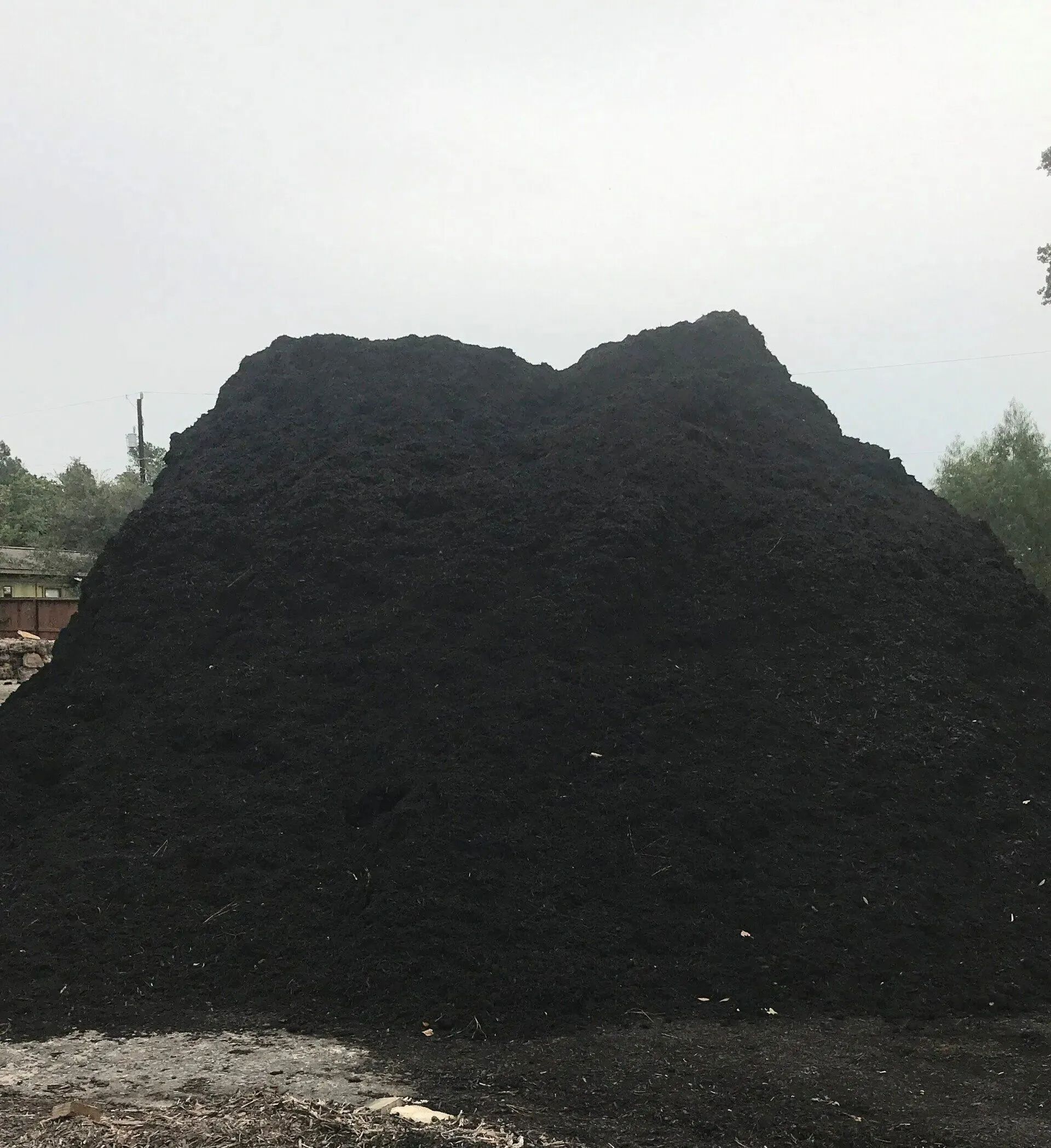 Large black coal pile outdoors against a pale sky.