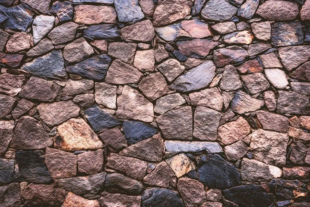 Close-up of a stone wall made of irregular brown, gray, and pink rocks