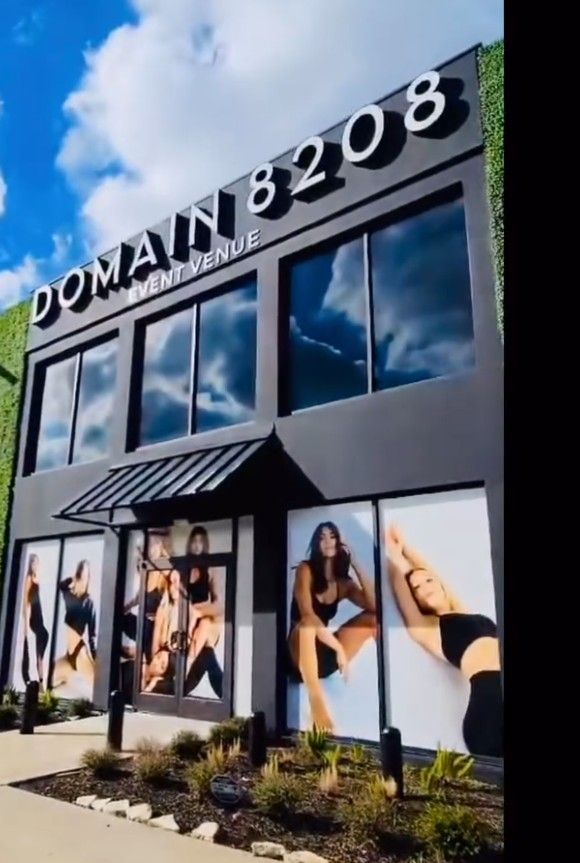 Domain 8208 storefront with large windows, posters, and a black awning under a blue sky