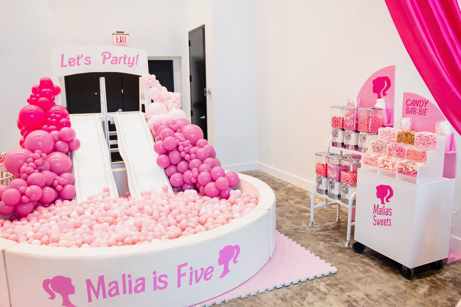Pink party dessert display with a balloon arch, “Let’s Party” sign, and “Malia is Five” banner.