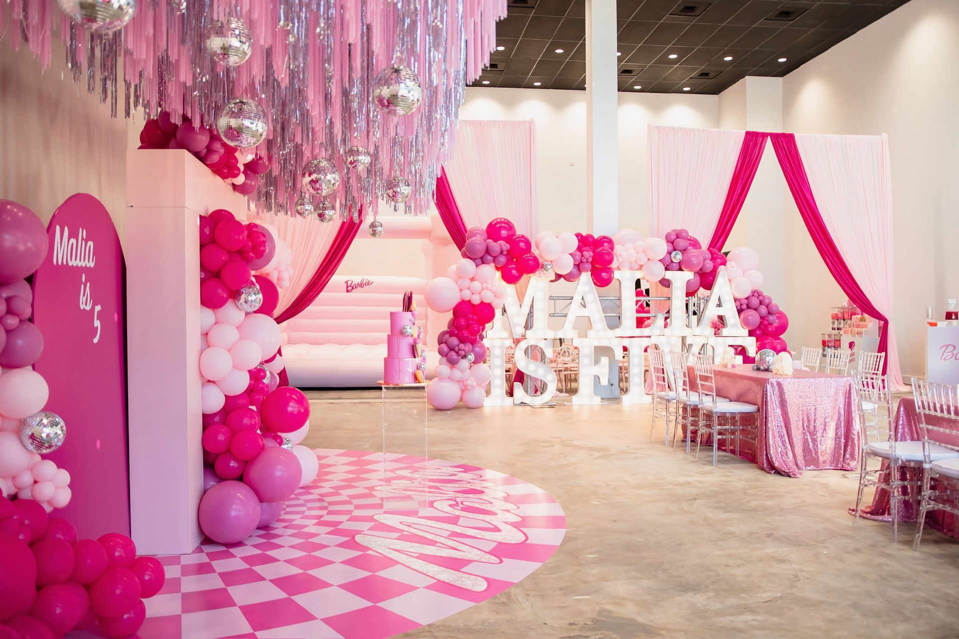 Pink-themed party setup with balloons, streamers, and a checkered dance floor