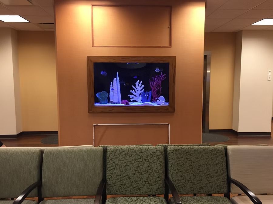 Awaiting area with an aquarium and green patterned chairs.