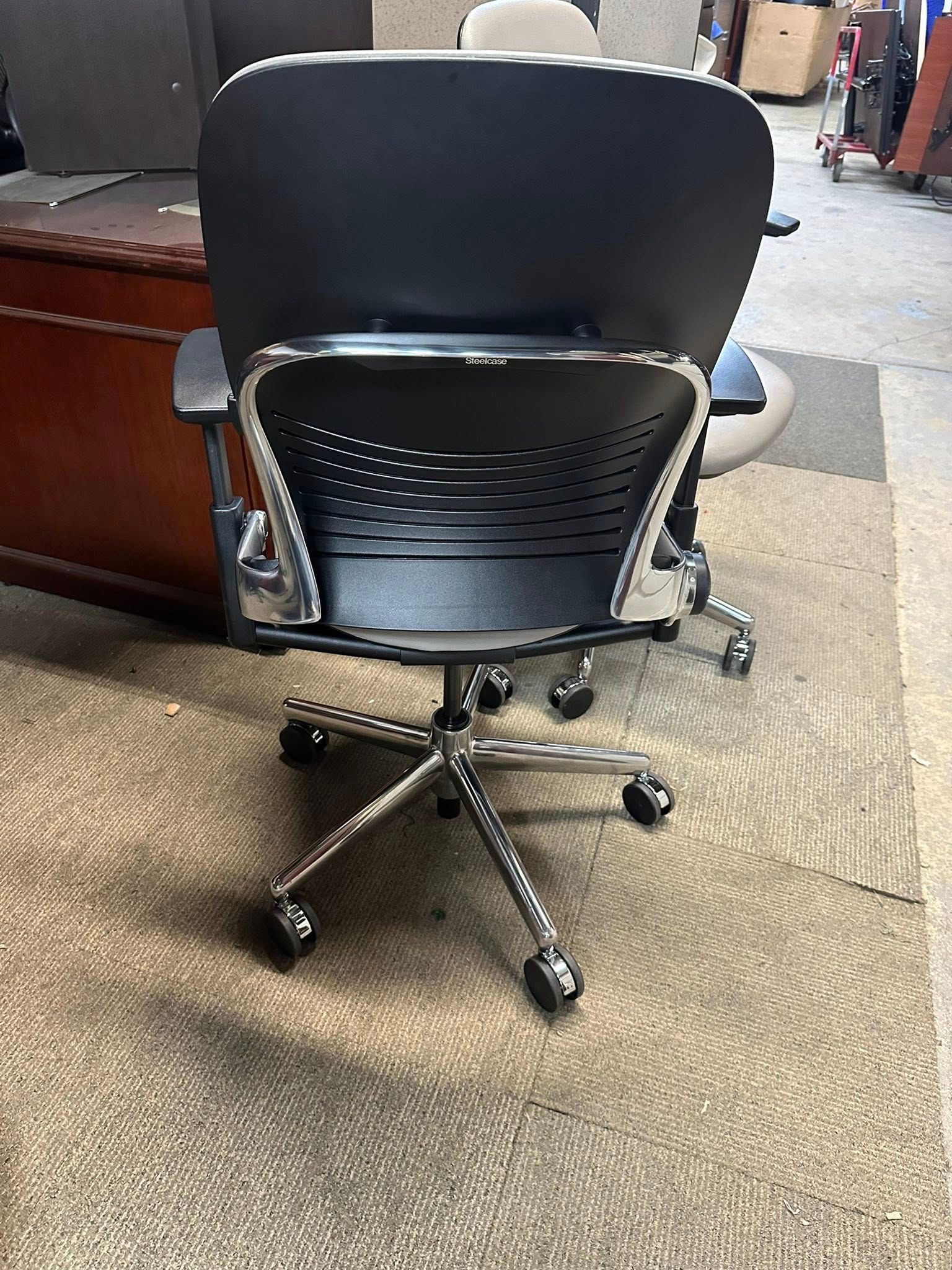 Black office chair with a mesh back and chrome base, on a patterned rug.