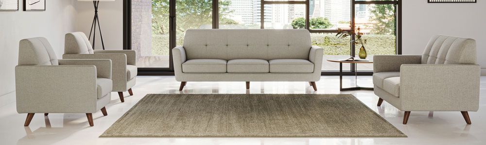 Living room with beige furniture set on a rug in front of a window.