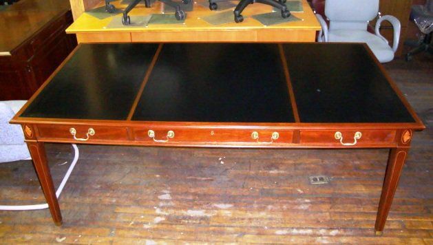 Wooden desk with three black panels, three drawers, and gold handles.