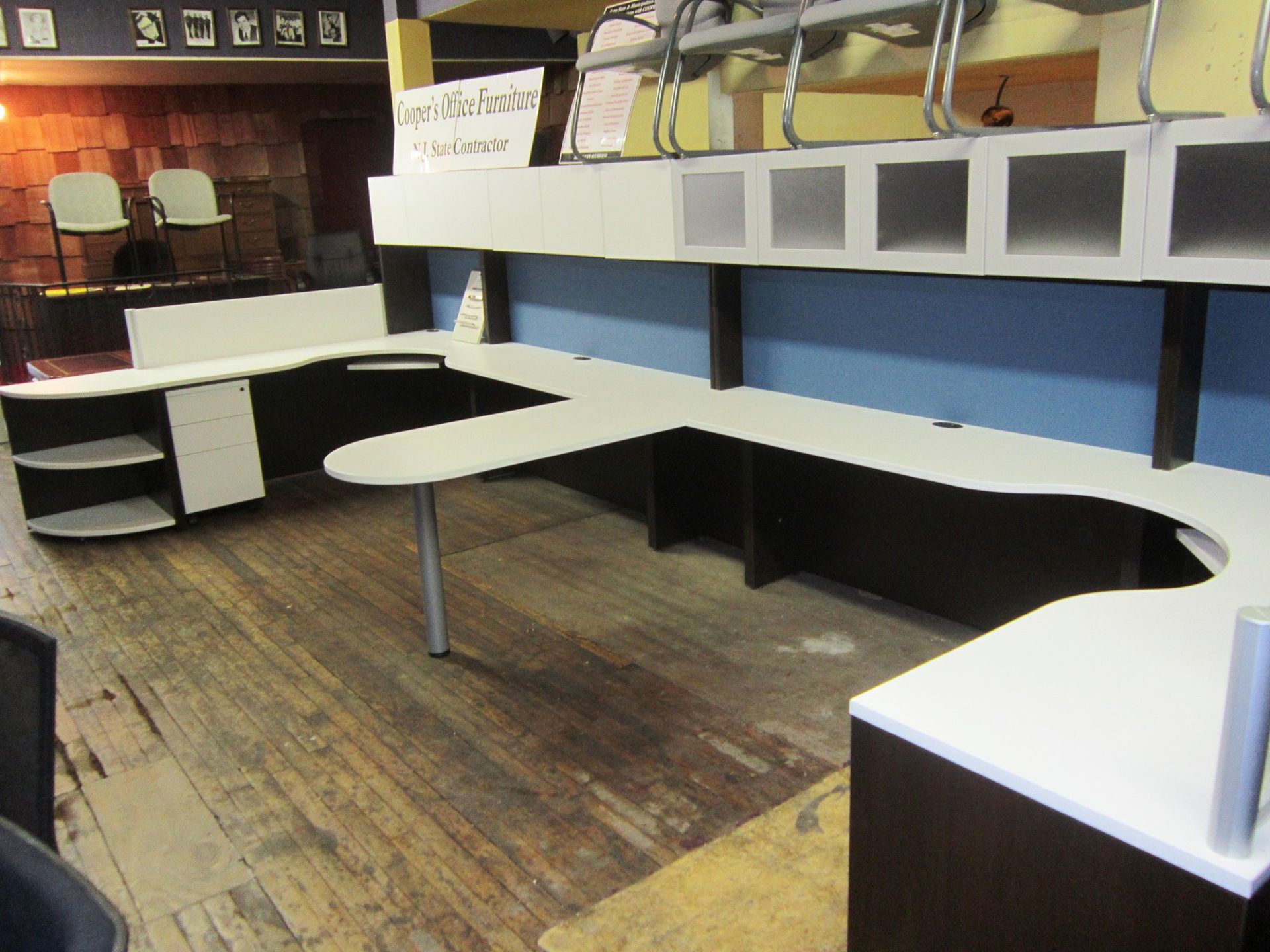 Office space with white and dark wood cubicle desks and storage cabinets.