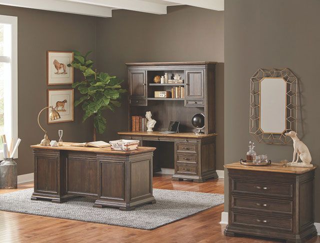 A dark brown home office with a desk, hutch, file cabinet, mirror, and decor.