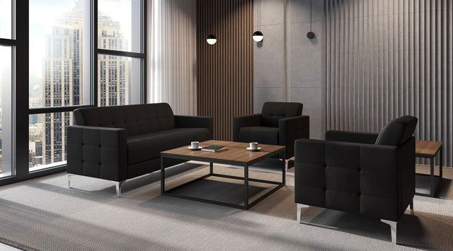 Modern office lounge area with dark gray sofas, coffee table, and city view.