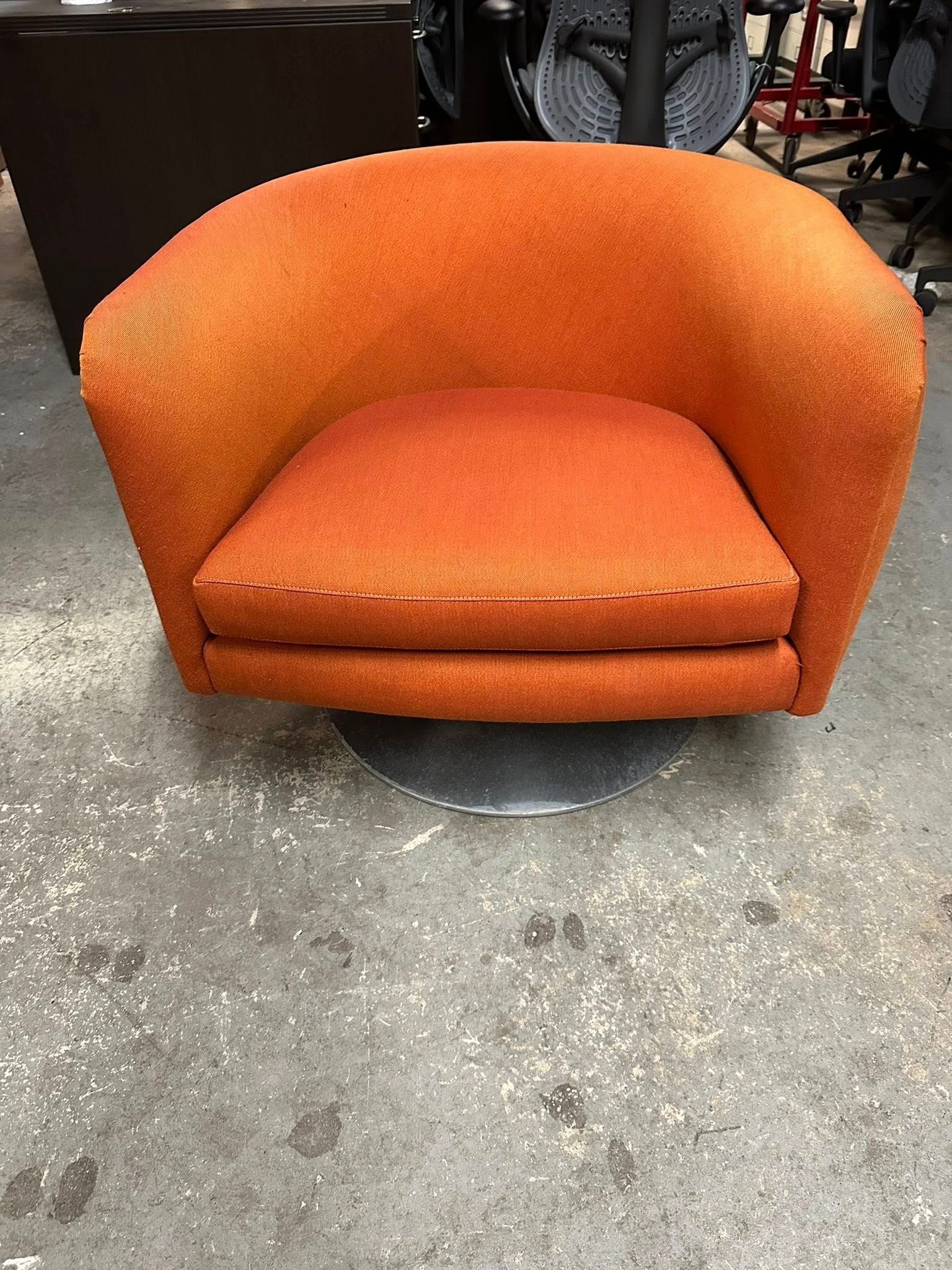 Orange swivel chair with rounded back and seat, on a metal base.