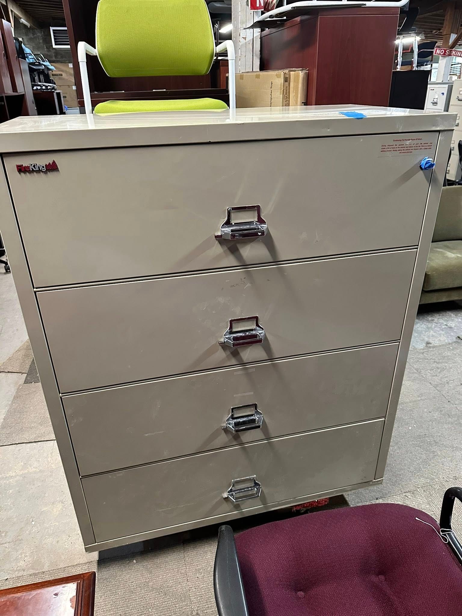 Tan metal filing cabinet with four drawers; drawers have handles and locks.