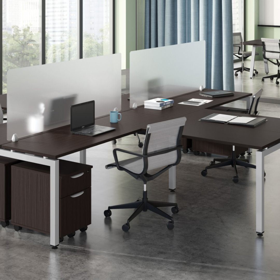 Office cubicles with dark brown desks, clear dividers, and gray chairs.