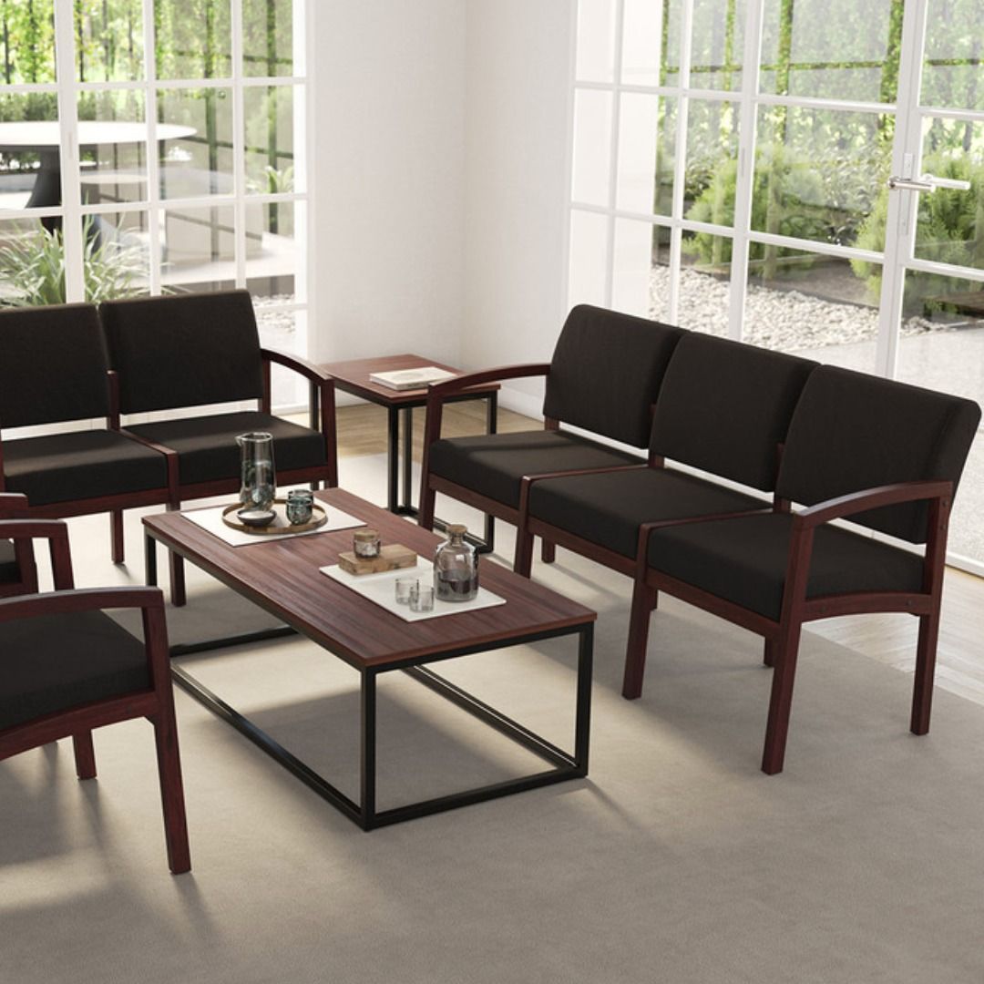Living room with black sofas, coffee table, and side table. Large windows provide natural light.