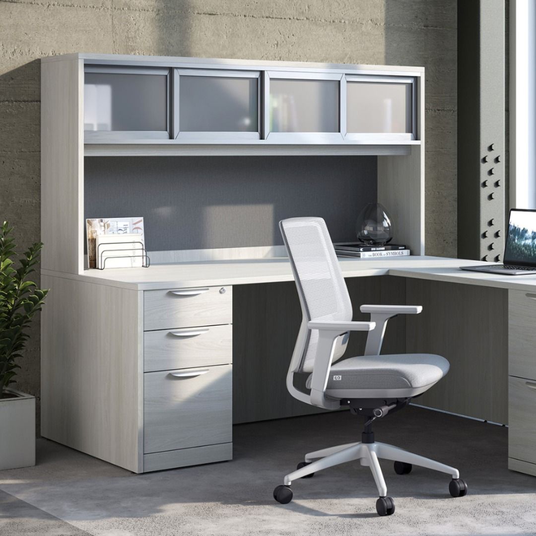 White office desk with overhead storage, chair, and decorative plant in a modern room.