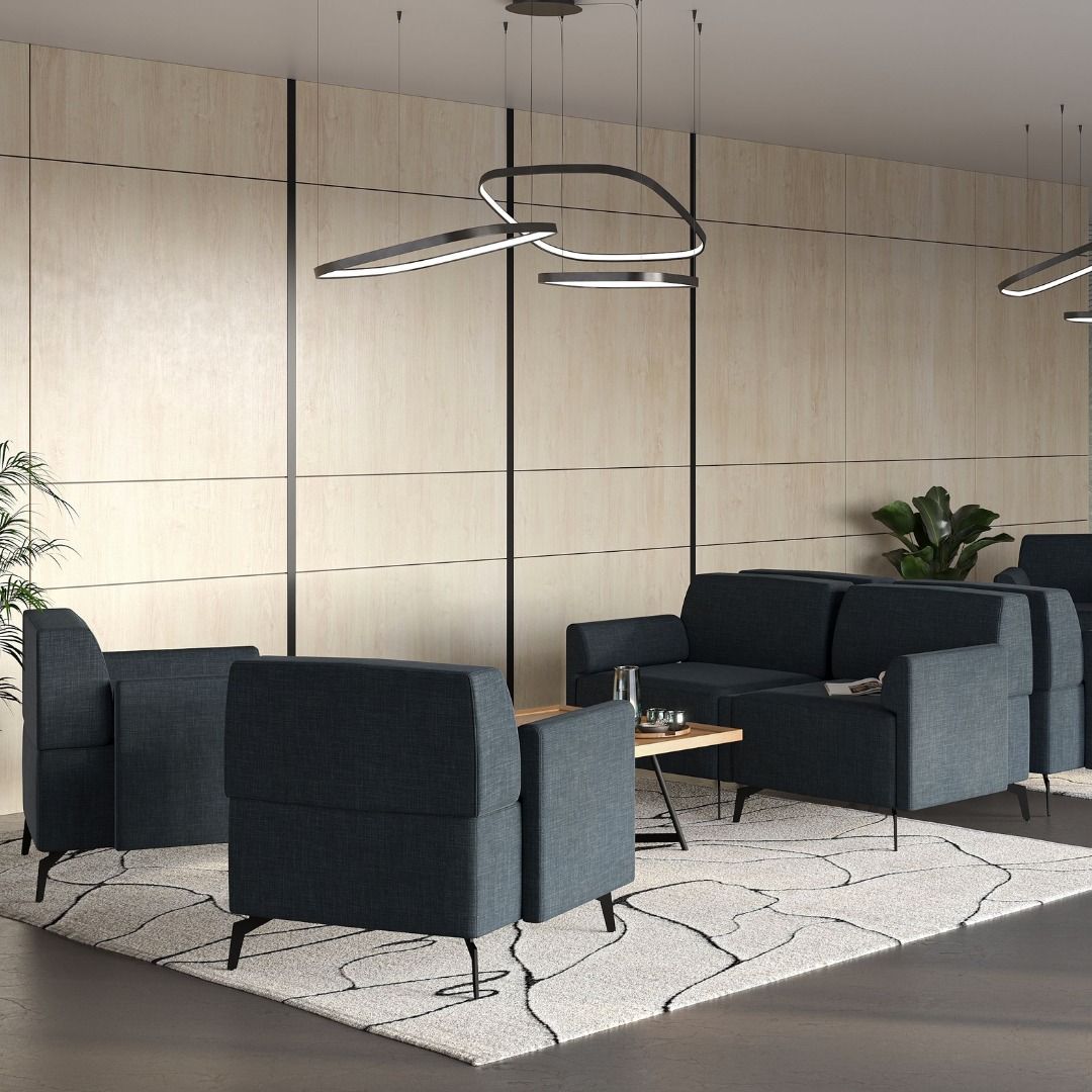 Modern waiting room with blue sofas, coffee table, rug, wood paneling, and pendant lights.