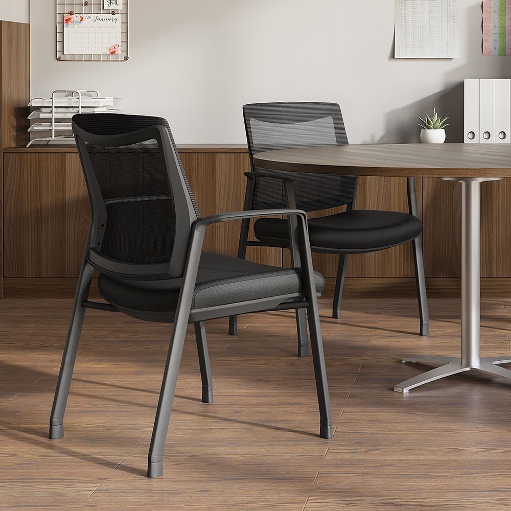 Two black mesh office chairs by a round table; paperwork and calendar in background.