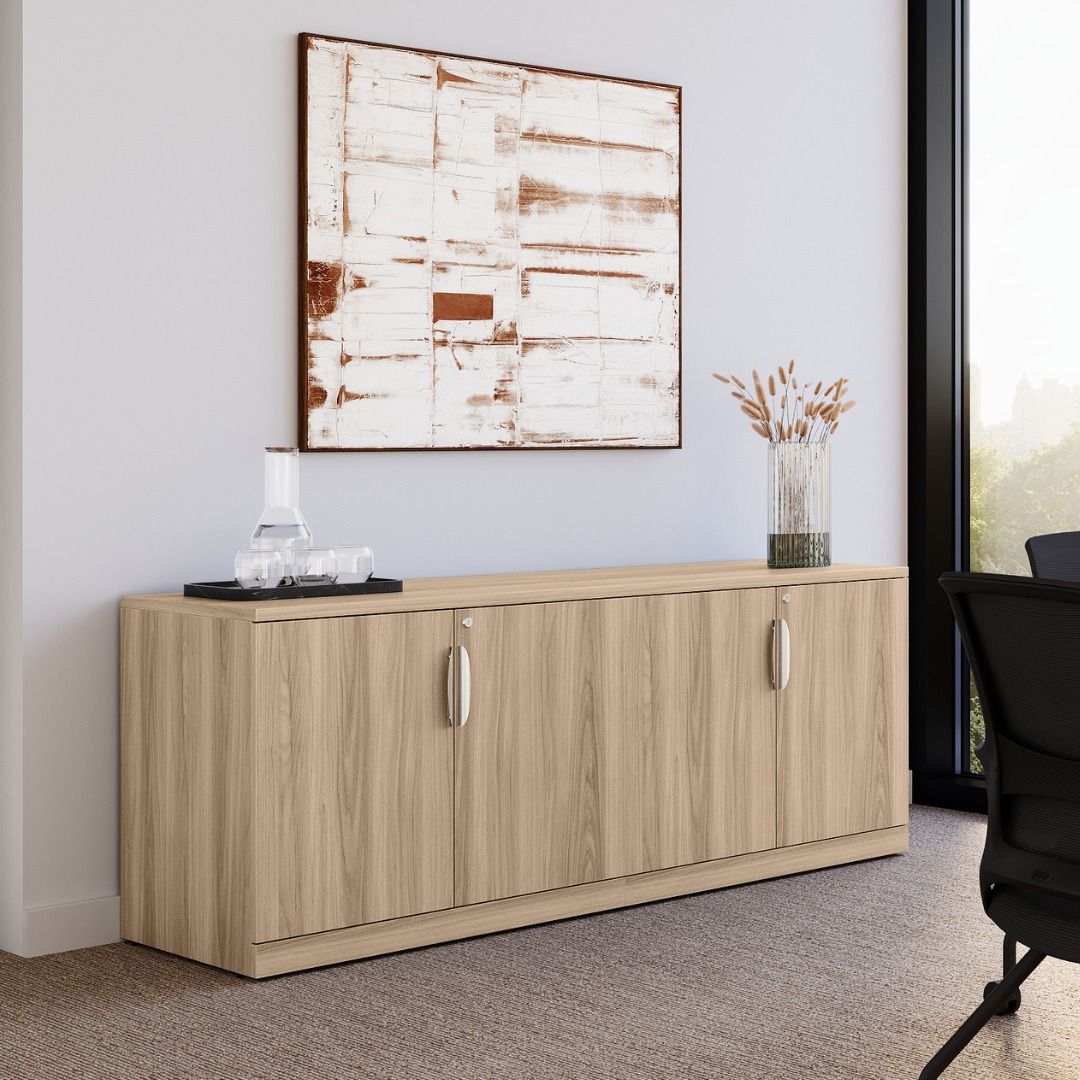 Wooden cabinet against a wall with artwork and a vase.