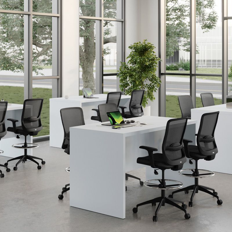 Modern office with white desks, black chairs, and large windows with a view.