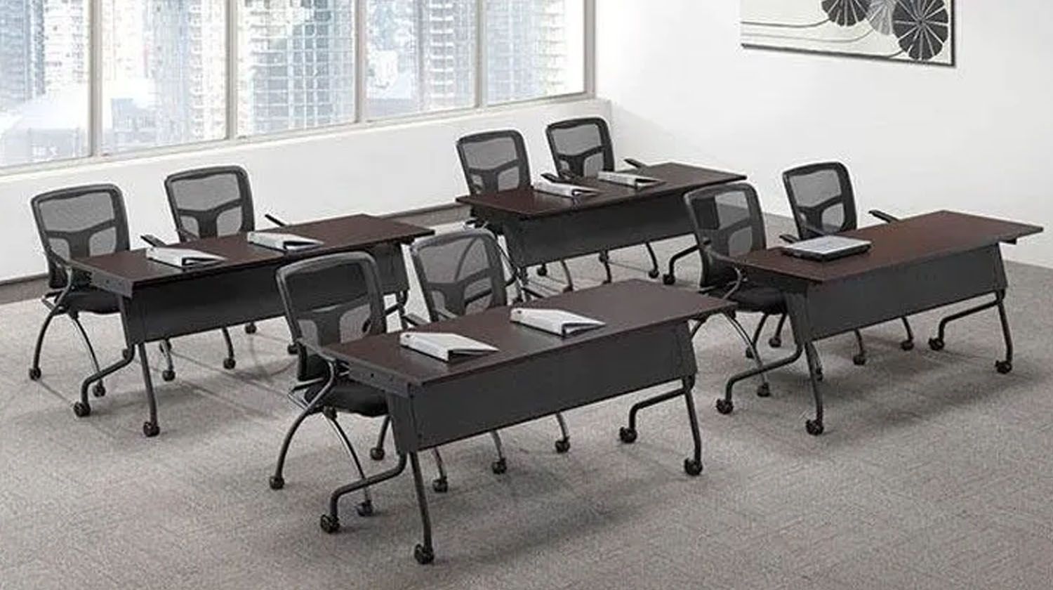 Office with several dark desks and chairs, arranged for meetings; windows and artwork in background.