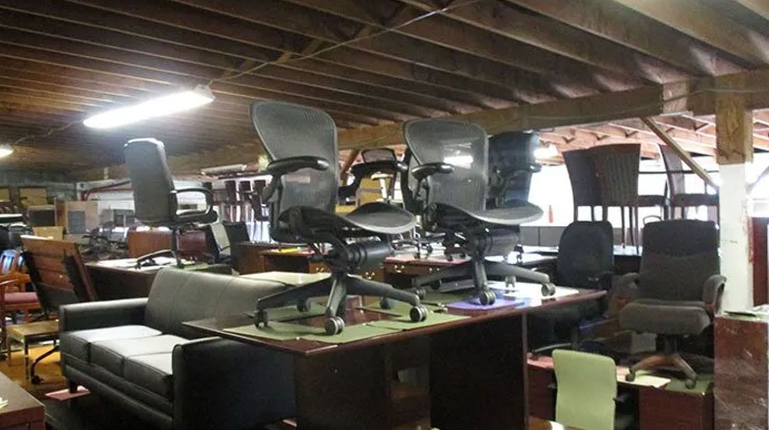 Warehouse filled with various used office chairs and furniture on display.