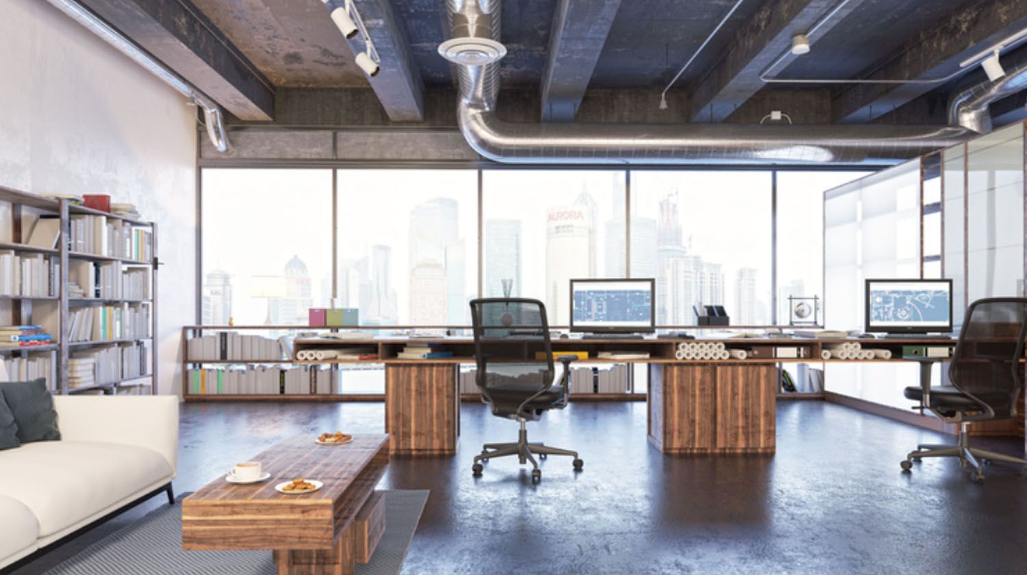 Modern office with large windows overlooking a city skyline, desks, and a bookshelf.