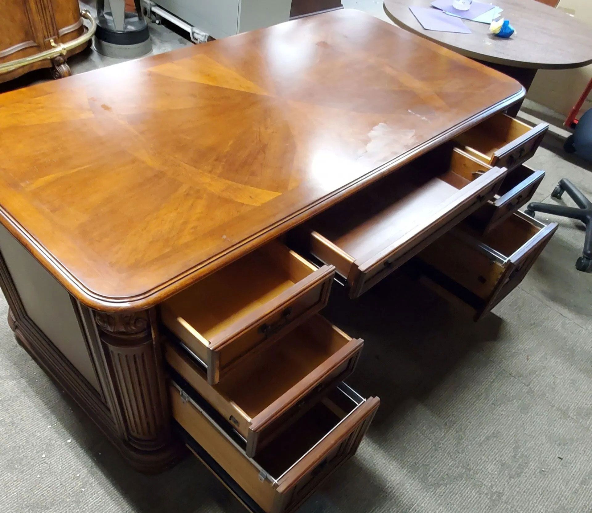 Wooden office desk with open drawers.